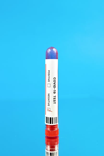 Red COVID-19 test tube with label on blue reflective background.